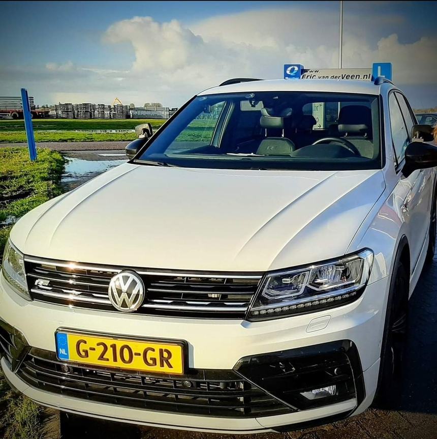 De witte Volkswagen Tiguan lesauto van Autorijschool Eric van der Veen met daklichtbak en L-bord